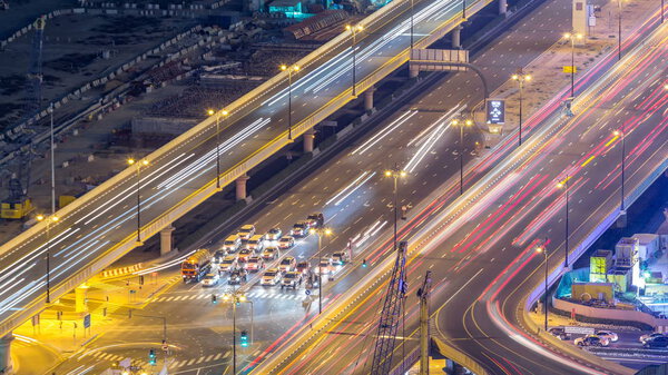 Night traffic on a busy intersection at Dubai downtown highway aerial timelapse. View from rooftop near mall