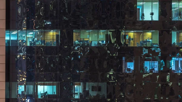 Windows çok katlı binanın içinde aydınlatma ve insanlar timelapse içinde hareketli çelik ve cam. Modern ofis gökdelenler Dubai Hava görünümünü. Sağa çevir