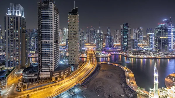 Residential towers with lighting and illumination timelapse. Water canal and promenade on Dubai Marina skyline at night. Floating yachts and boats with traffic near skyscrapers