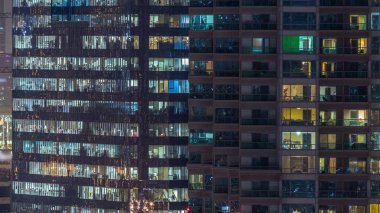 Windows çok katlı binanın içinde aydınlatma ve insanlar timelapse içinde hareketli çelik ve cam. Modern konut ve ofis gökdelenler Dubai Marina havadan görünümü.