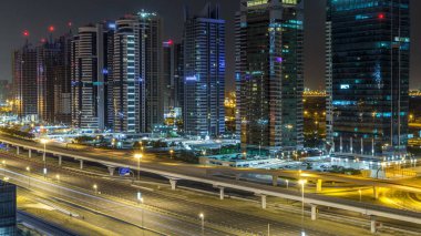 Jumeirah lakes hava görünümünü ışıklandırılmış gökdelenler ile Şeyh zayed road ve metro hattı üzerinde trafik ile bütün gece timelapse sırasında kuleleri. Dubai Yat Limanı çatı görünümü