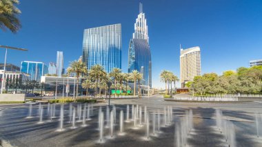 Çeşmeler en yüksek gökdelen timelapse hyperlapse, Dubai ana girişe yakın. Palmiye ve arka plan üzerinde modern kuleli güneşli gün, downtown Dubai yolda trafik