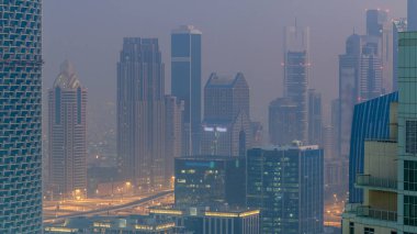 Sisli sabah gün geçiş timelapse gecesine Dubai şehir merkezinde. Şehir gökdelenler fütüristik görünümünü Şeyh zayed yolu üzerinde sis kaplı. Çatı güneş doğmadan önce havadan görünümden. Dubai, Birleşik Arap Emirlikleri