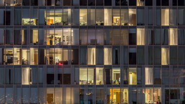 Yanıp sönen ve windows çok katlı binanın cam ve çelik iç aydınlatma ve insanlar timelapse içinde hareketli yanıp sönen. Dubai merkezinde modern konut gökdelenlerin havadan görünümü. Yakınlaştır