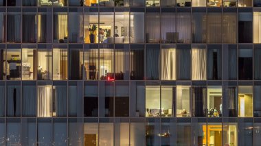 Yanıp sönen ve windows çok katlı binanın cam ve çelik iç aydınlatma ve insanlar timelapse içinde hareketli yanıp sönen. Dubai merkezinde modern konut gökdelenlerin havadan görünümü