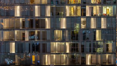 Yanıp sönen ve windows çok katlı binanın cam ve çelik iç aydınlatma ve insanlar timelapse içinde hareketli yanıp sönen. Dubai merkezinde modern konut gökdelenlerin havadan görünümü. Yukarı kaydır