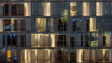 Yanıp sönen ve windows çok katlı binanın cam ve çelik iç aydınlatma ve insanlar timelapse içinde hareketli yanıp sönen. Dubai merkezinde modern konut gökdelenlerin havadan görünümü. Pan sol