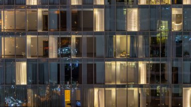 Yanıp sönen ve windows çok katlı binanın cam ve çelik iç aydınlatma ve insanlar timelapse içinde hareketli yanıp sönen. Dubai merkezinde modern konut gökdelenlerin havadan görünümü