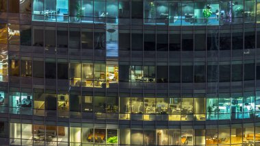 Windows çok katlı binanın içinde aydınlatma ve insanlar timelapse içinde hareketli çelik ve cam. Dubai merkezinde modern ofis gökdelenlerin havadan görünümü. Vınlamak dışarı