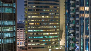 Windows çok katlı binanın içinde aydınlatma ve insanlar timelapse içinde hareketli çelik ve cam. Modern konut ve ofis gökdelen içinde Dubai deira hava görünümünü. Yakınlaştır