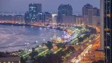 Dubai creek peyzaj gün gece geçiş timelapse tekneler ve yatlar ile ve trafik yol ve otopark ile modern binalar. Yukarıdan hava üstten görünüm