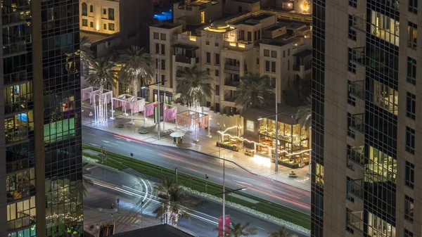 Birds eye view of Dubai skyline timelapse and rush hour traffic in downtown at night. Road with palms between houses