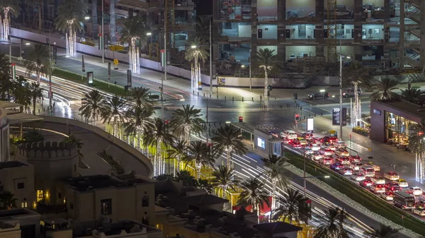 Birds eye view of Dubai skyline timelapse and rush hour traffic in downtown at night. Road with palms with intersection