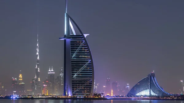 Dubai, Birleşik Arap Emirlikleri - Mart 2018 yaklaşık: Skyline Dubai gece Burj Al Arab Palm Jumeirah timelapse dan ile. Suya yansıyan ışıklandırılmış gökdelenler