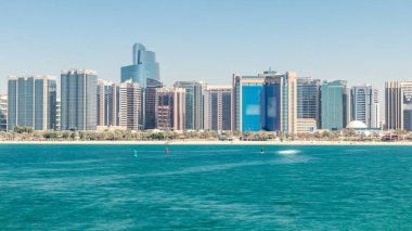 Abu Dabi 'de, kültür köyü yakınlarındaki Breakwater' dan gelen yüksek gökdelenlerle dolu iş merkezinin yanında uzanan bir korniş manzarası.
