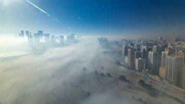 Sabah, en büyük ve en kalabalık şehri Birleşik Arap Emirlikleri Abu Dabi timelapse sokak, kalın sis altında silueti. Gündoğumu sonra yukarıdan gökdelenlerin havadan görünümü
