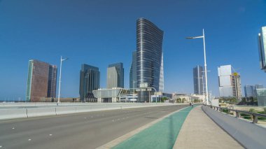 Abu Dabi 'deki Al Maryah Adası' nın modern binaları yol trafiğiyle birlikte zaman çizgisi aşırı hızlanıyor. Köprüden bak ve gökdelenlere yansıt