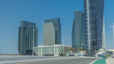 Abu Dabi 'deki Al Maryah Adası' nın modern binaları yol trafiğiyle birlikte ufuk çizgisi zaman çizelgesi. Gökdelenleri yansıtan köprüden görünüm
