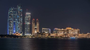 Abu Dabi Etihad Kuleleri binalar ve emirates palace timelapse ile gece ışıklı gökdelenler. Abu Dhabi Birleşik Arap Emirlikleri ikinci en kalabalık kenti başkentidir