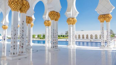 Birleşik Arap Emirlikleri 'nin başkenti Abu Dabi' deki Şeyh Zayed Büyük Camii zaman çizelgesi. Sütunlar arasında yürüyen insanlar. Güneşli bir günde mavi gökyüzü
