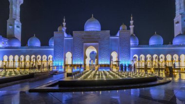 Şeyh Zayed 'in Ulu Camii gece saatlerinde aydınlandı. Aşırı hız, Abu Dabi, BAE. Çeşmeli ön manzara. Dünyanın en büyük üçüncü camii.