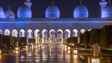 Şeyh Zayed 'in Ulu Camii gece vakti aydınlandı. Abu Dabi, BAE. Yansımalı yan görüş. Dünyanın en büyük üçüncü camii.