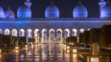 Sheikh Zayed Grand Mosque illuminated at night timelapse, Abu Dhabi, UAE. Side view with reflections. The 3rd largest mosque in the world clipart