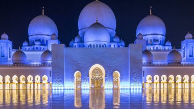 Şeyh Zayed 'in Ulu Camii gece vakti aydınlandı. Abu Dabi, BAE. İç avluda yerde yansımalar var. Dünyanın en büyük üçüncü camii.