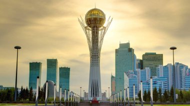 Astana, Kazakistan - Temmuz 2016: Bayterek güzel günbatımı timelapse Kazakistan Astana sermaye kulede. Modern binalar ve gökdelenler arka plan üzerinde. Turuncu Gökyüzü
