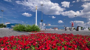 Astana, Kazakistan stel anıt kazak Eli ile kuş Samruk ve Bağımsızlık Sarayı timelapse hyperlapse ve kırmızı flowerbed ön planda. Kazakistan, 1991 yılında bağımsızlığını kazandı. Anıt 91 metre yüksekliği. 4k