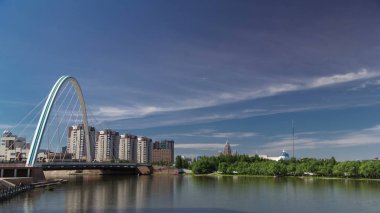 Park timelapse taşıma ve arka planda bulutlar ile Ishim üzerinde köprü. Şehir manzarası. Orta Asya, Kazakistan Astana 4k