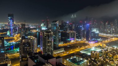 Gece timelapse gece trafik ve ışıklandırılmış gökdelenler, ofis binaları ile büyük modern bir şehir doğal hava görünümünü. İş bay, Dubai, Birleşik Arap Emirlikleri.