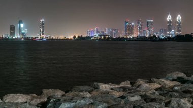 Dubai Internet City ve kazım kuleleri timelapse palm jumeirah sudan geceleri taşları dalgakıran alt ile yansıtılır