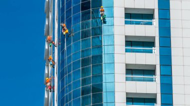 Dubai, BAE 'deki modern gökdelenin camlarını siliyorlar. Güneşli günde manzarayı kapat