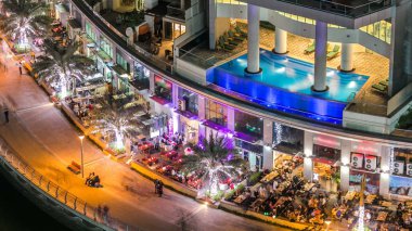 Dubai Yat Limanı mesire restoran ve kanal kayan yat ve tekne Dubai, Birleşik Arap Emirlikleri ile gece timelapse güzel hava en iyi manzaraya. Yanıp sönen ışıklar ve yolda trafik ile ışıklı modern kuleleri. 