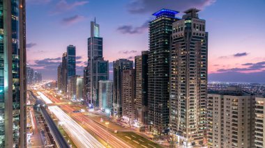 Dubai Kuleleri 'nin şehir merkezinden gece gündüz geçiş zamanı. Gün batımından sonra Şeyh Zayed 'in gökdelenli hava manzarası. Yollarda ve metro hattında trafik vardı. Güzel bulutlu gökyüzü