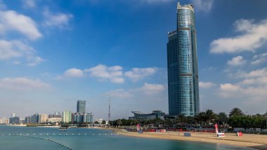 Abu Dabi timelapse hyperlapse Basra Körfezi, BAE kumsalda ile Cityscape. Abu Dabi ve Birleşik Arap Emirlikleri ile yaklaşık 1 milyon kişi ikinci en kalabalık şehirde başkentidir. Mavi bulutlu gökyüzü