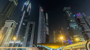 Dubai Kuleleri 'nin aşağısında gece vakti aşırı hızlanma. Şeyh Zayed 'in yüksek gökdelenli manzarası. Yollarda ve metro hattında trafik vardı. Yanıp sönen ışıklar ve patikalar
