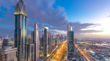 Gece geçiş timelapse doğal Dubai şehir mimarisi günler. Üstten Görünüm ışıklandırılmış gökdelenler ve trafik ile Şeyh Zayed Yolu üzerinde. Güzel bulutlu gökyüzü