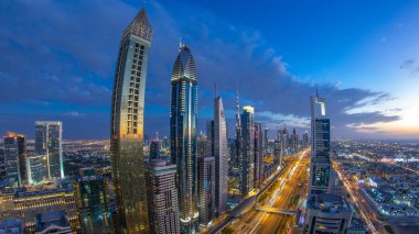 Gece geçiş timelapse doğal Dubai şehir mimarisi günler. Üstten Görünüm ışıklandırılmış gökdelenler ve trafik ile Şeyh Zayed Yolu üzerinde. Güzel bulutlu gökyüzü. Balık gözü lens