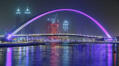 Jumeirah Beach Deira, Downtown Dubai ve Safa Park ile dokuma Dubai Creek bağlandığı Dubai su kanalı gece timelapse ışıklı yaya köprüsü. Gökdelenler manzarası. Dubai, Birleşik Arap Emirlikleri