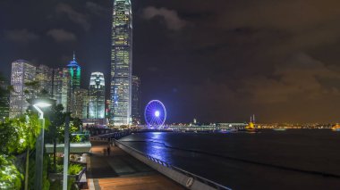 Skycrapers gece timelapse ve kentin en son turist çeken Hong Kong gözlem tekerleği. Dolgu ve su yansıması ile görüntüleyin. 4k