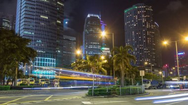 Gece görünümü hyperlapse yakın otobüs durağı gökdelenler ile kavşak üzerinde karşısında modern şehir trafik. Zaman atlamalı. Hong Kong. 4k