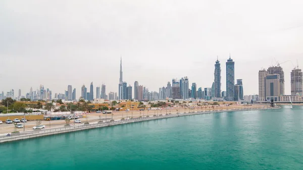 The new Dubai Water Canal with view on the city skyline cloudy day timelapse, United Arab Emirates. Skyscrapers reflected in water. View from bridge