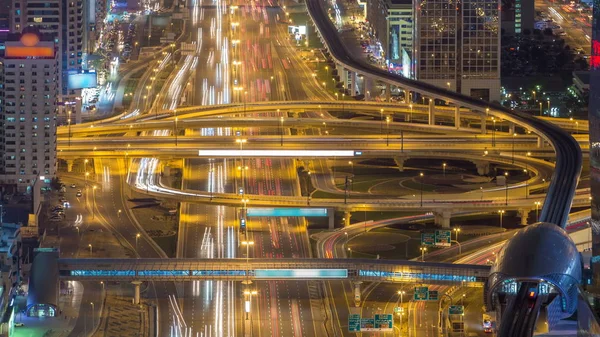 Aerial top view of highway junction with traffic timelapse in Dubai, UAE, at night. Famous Sheikh Zayed road in Dubai downtown. Transportation and driving concept view from rooftop.