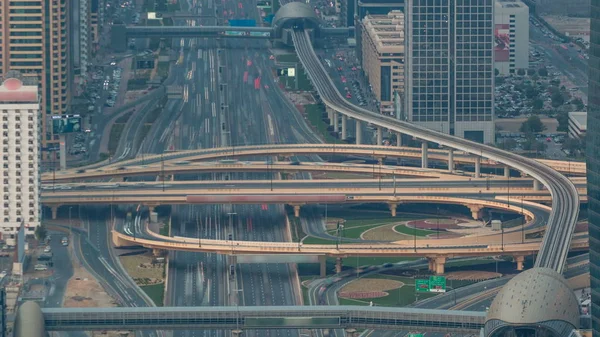 Aerial top view of highway junction with traffic timelapse in Dubai, UAE, at sunset. Famous Sheikh Zayed road in Dubai downtown. Transportation and driving concept view from rooftop.