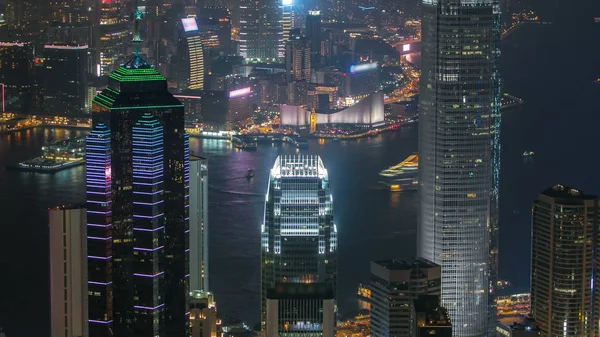 Hong Kong şehir manzarası timelapse Victoria Limanı ve dağ yakın üst görünümden görüntülendi su üzerinde ışıklar tarafından aydınlatılmış gökdelenler ile gece. 4k