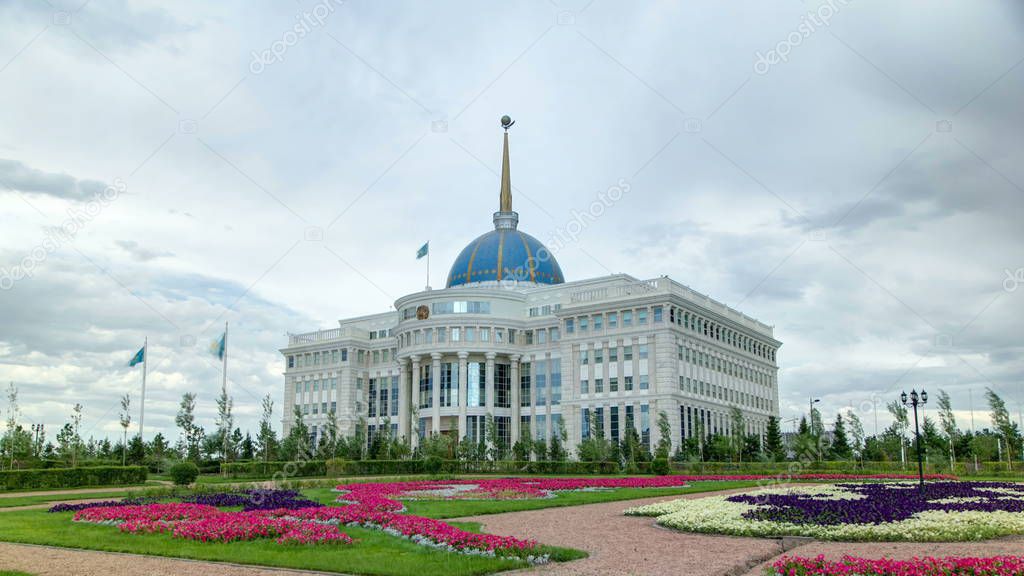 Entrance to Residence of the President of the Republic of Kazakhstan Ak Orda timelapse hyperlapse in Astana, Kazakhstan. Flowerbed in foreground. Cloudy sky at summer day.