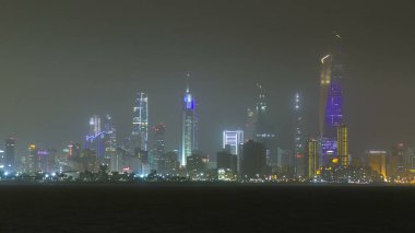 Manzarası ile gökdelenler gece timelapse Kuveyt City şehir merkezinde akşam aydınlatılmış. Kuveyt City, Orta Doğu. Sisli hava su yansıması ile plaja görüntülemek
