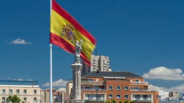 İspanyolca dalgaları Christopher Columbus timelapse bulutların üstünde mavi gökyüzü, plaza de Colon Madrid, İspanya 4 k ile heykelinin arkasında bayrak